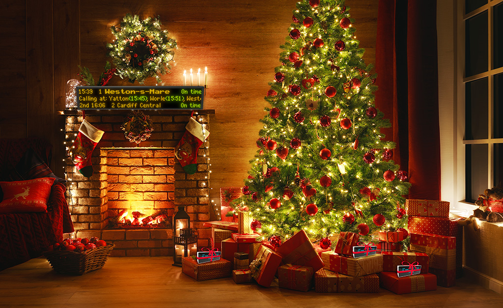 A UK Departure Boards Pro LED train departure board mounted above a fireplace at Christmas, showing live departures to Weston-super-Mare and Cardiff Central